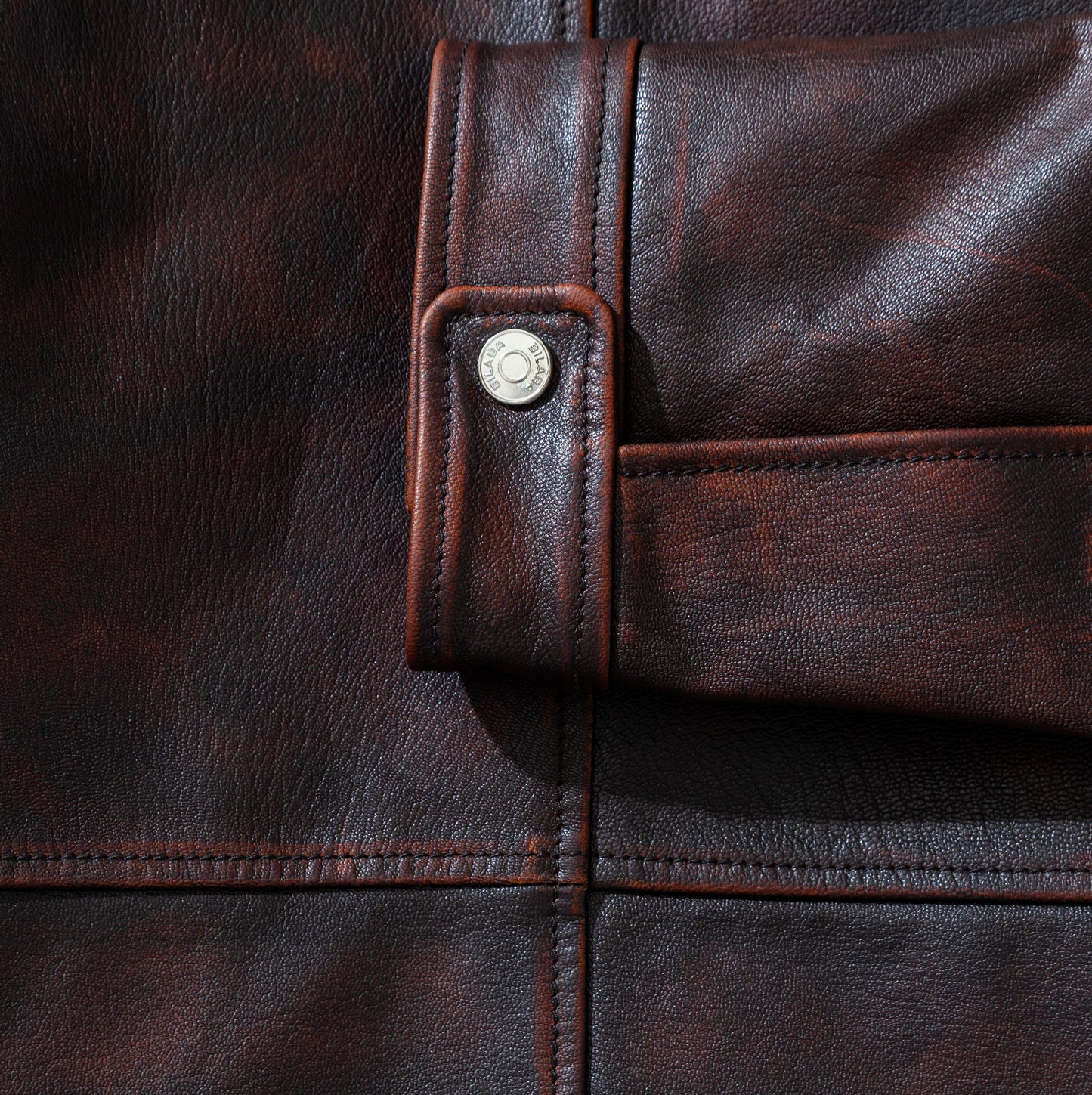 Close-up of a brown vintage leather jacket with a button detail
