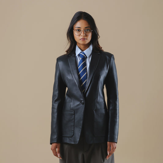 Person wearing a black leather blazer jacket and tie on a beige background