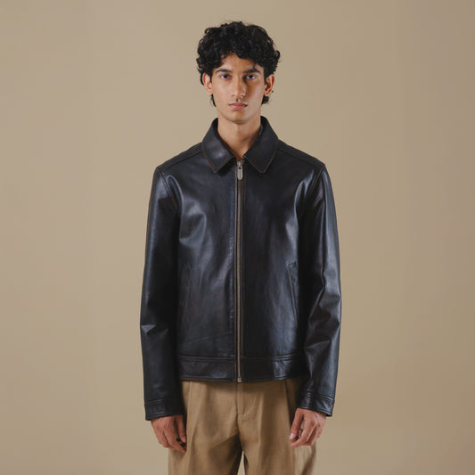Man wearing a black vintage leather jacket against a beige background