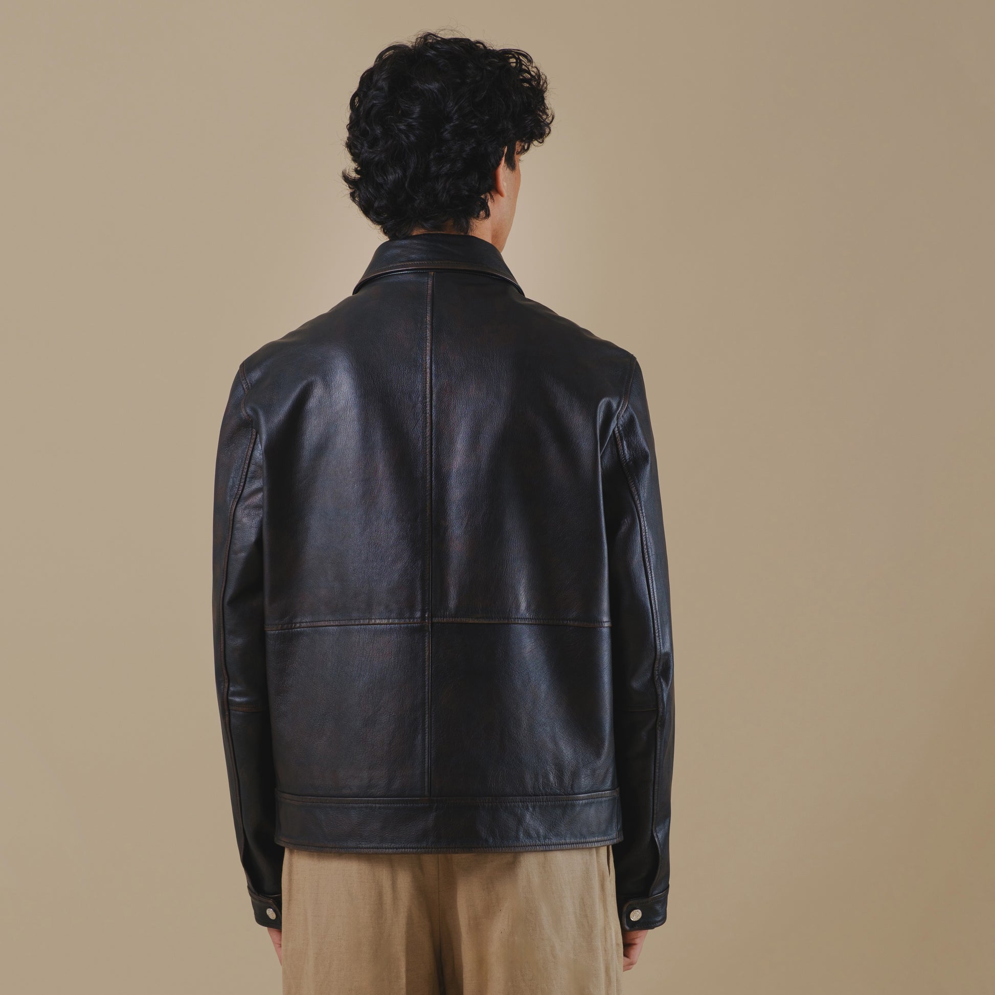 Man wearing a black vintage leather jacket on a beige background