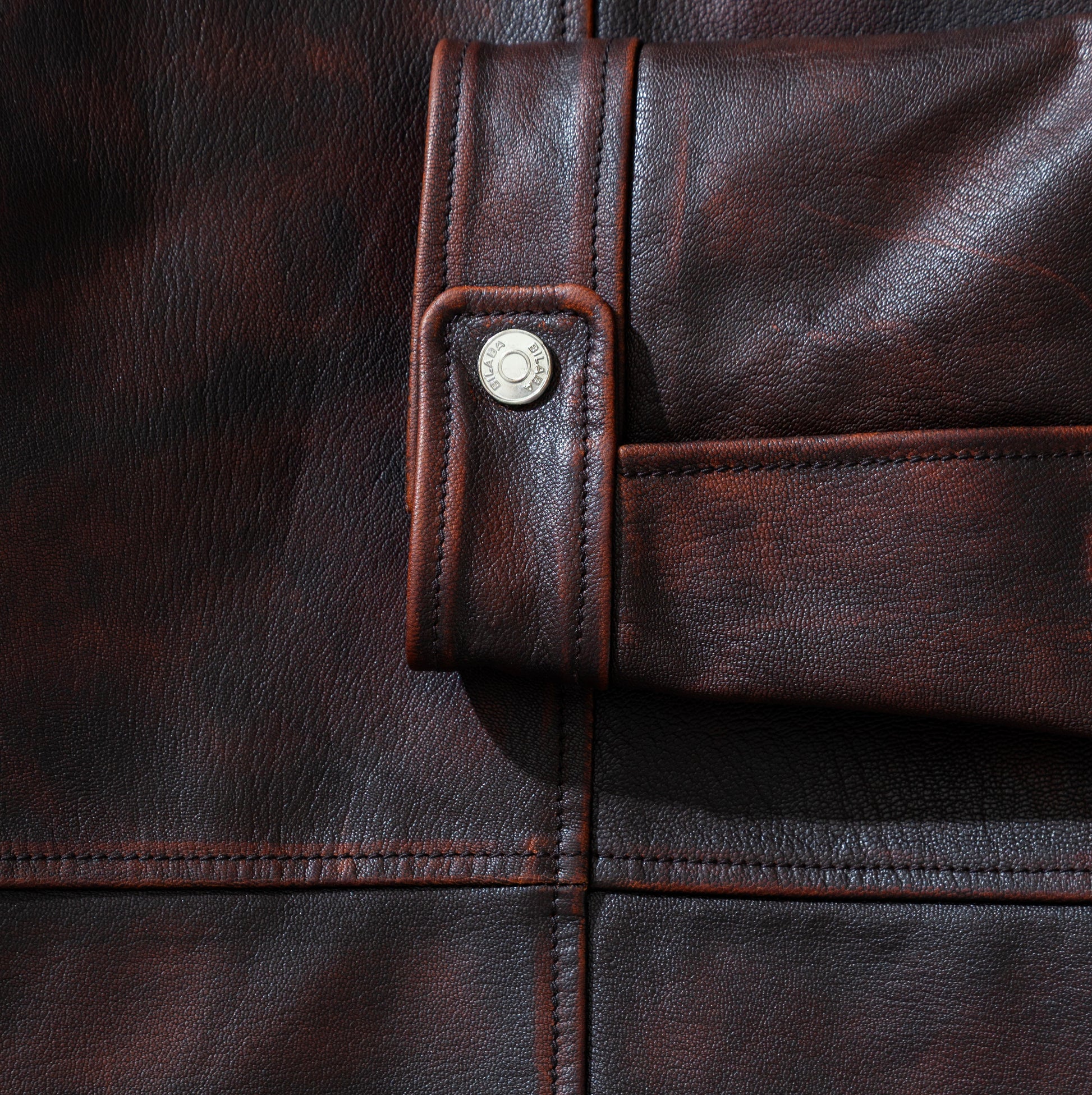 Close-up of a brown vintage leather jacket with a button detail