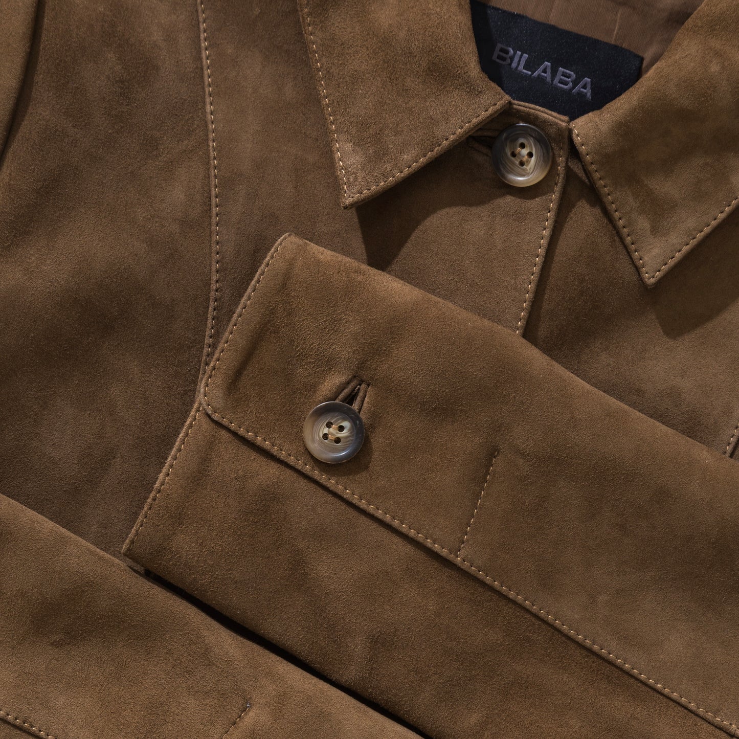 Close-up of a brown suede jacket with visible branding on the collar.