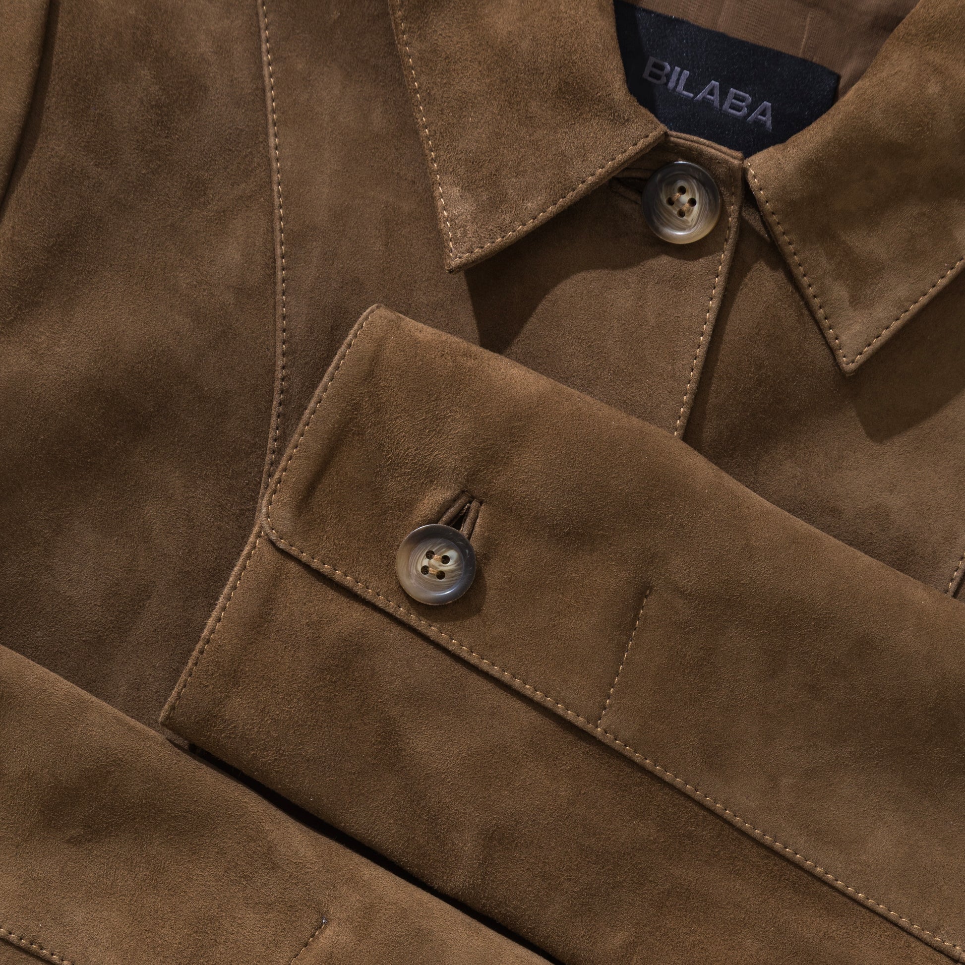 Close-up of a brown suede jacket with visible branding on the collar.