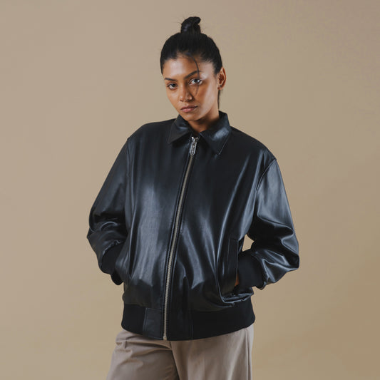 Woman wearing a black leather jacket against a beige background