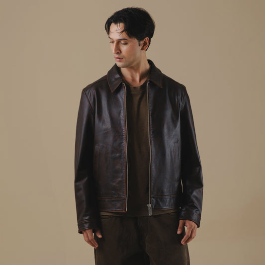 Man wearing a vintage brown leather jacket against a beige background