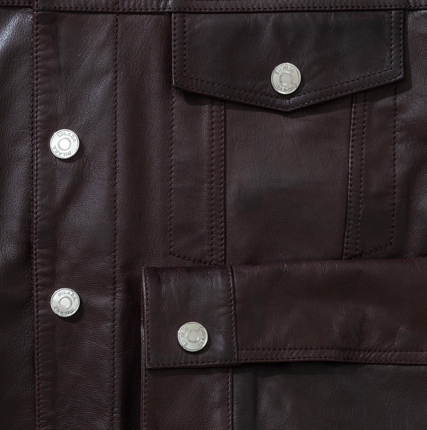 Close-up of a dark brown leather jacket with button details