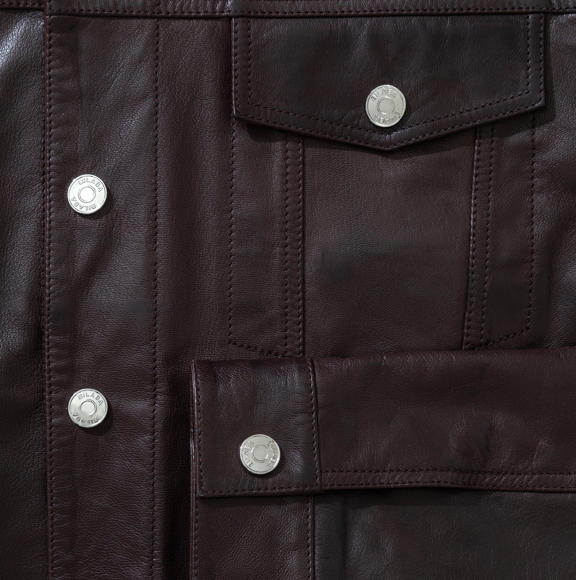 Close-up of a dark brown leather jacket with button details