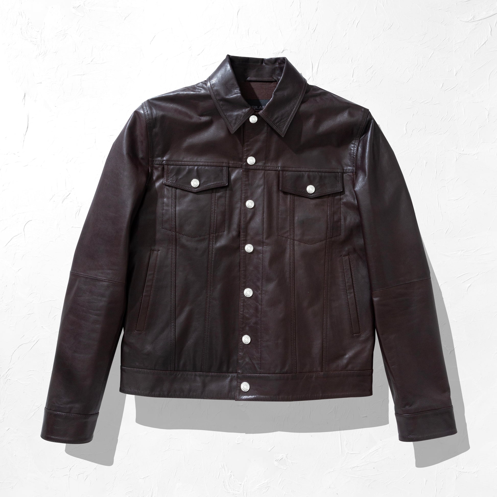 Dark brown leather jacket with white buttons on a light gray background
