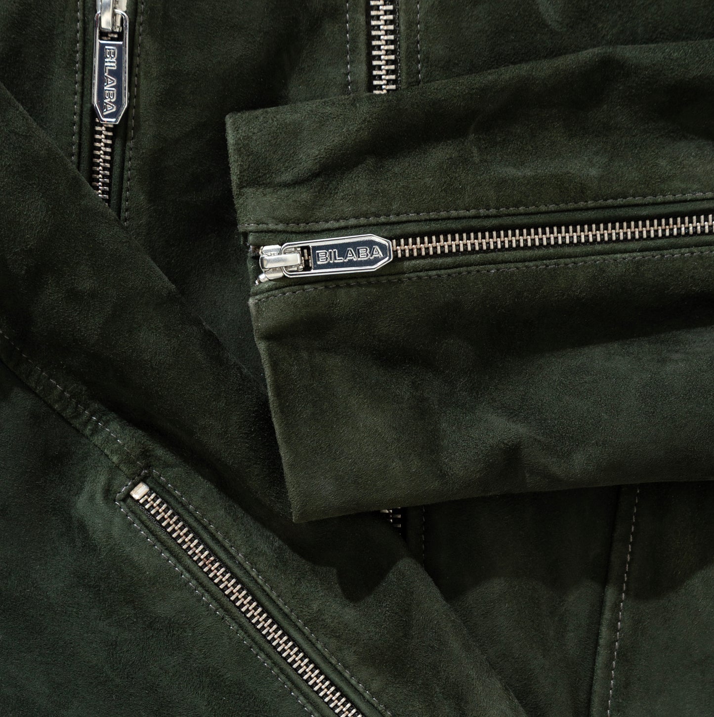 Close-up of a green suede jacket with zippers and 'BILABA' branding.