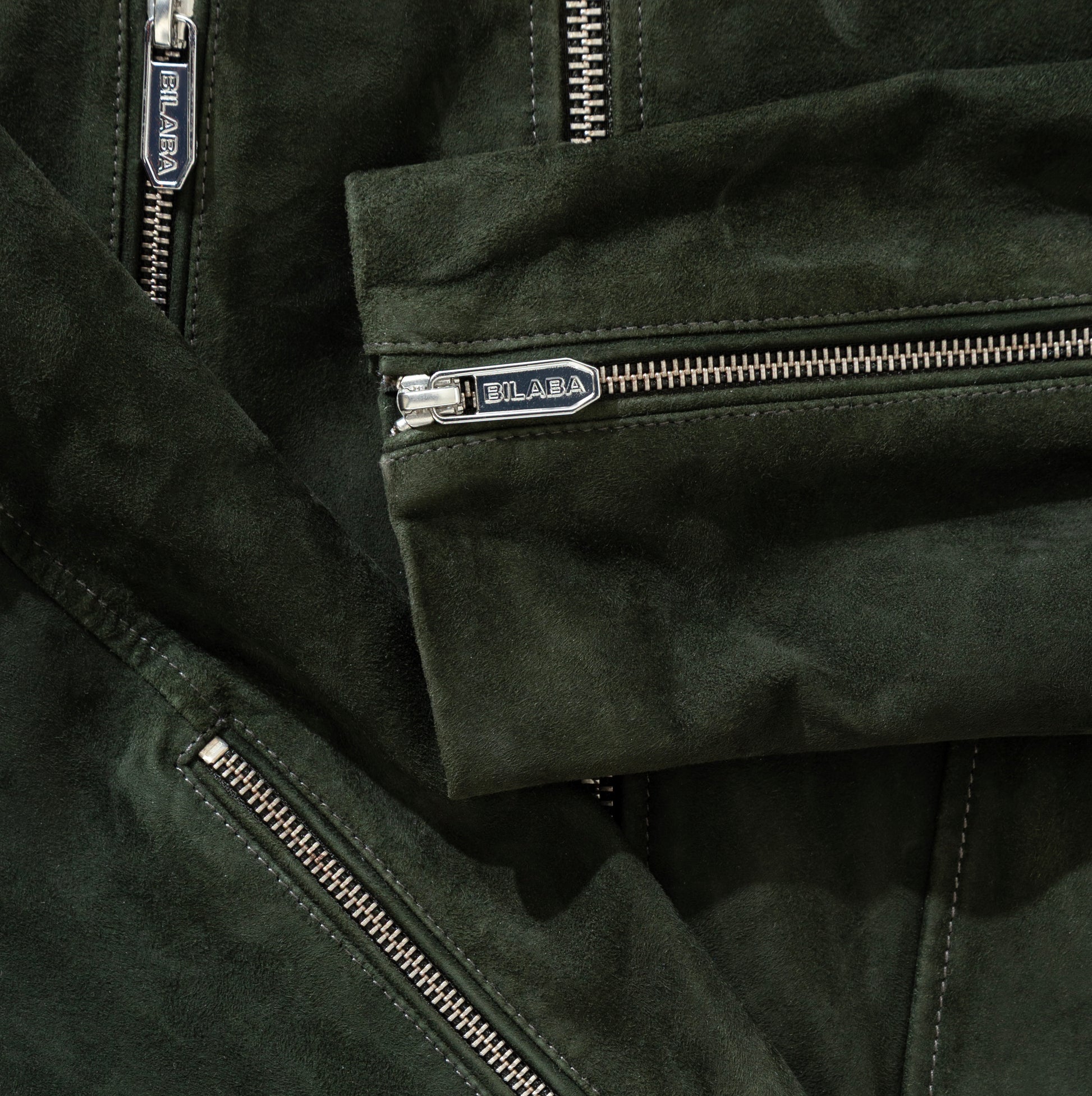 Close-up of a green suede jacket with zippers and 'BILABA' branding.