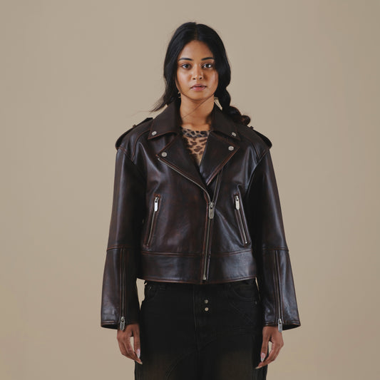 Woman wearing a brown vintage leather biker jacket against a beige background