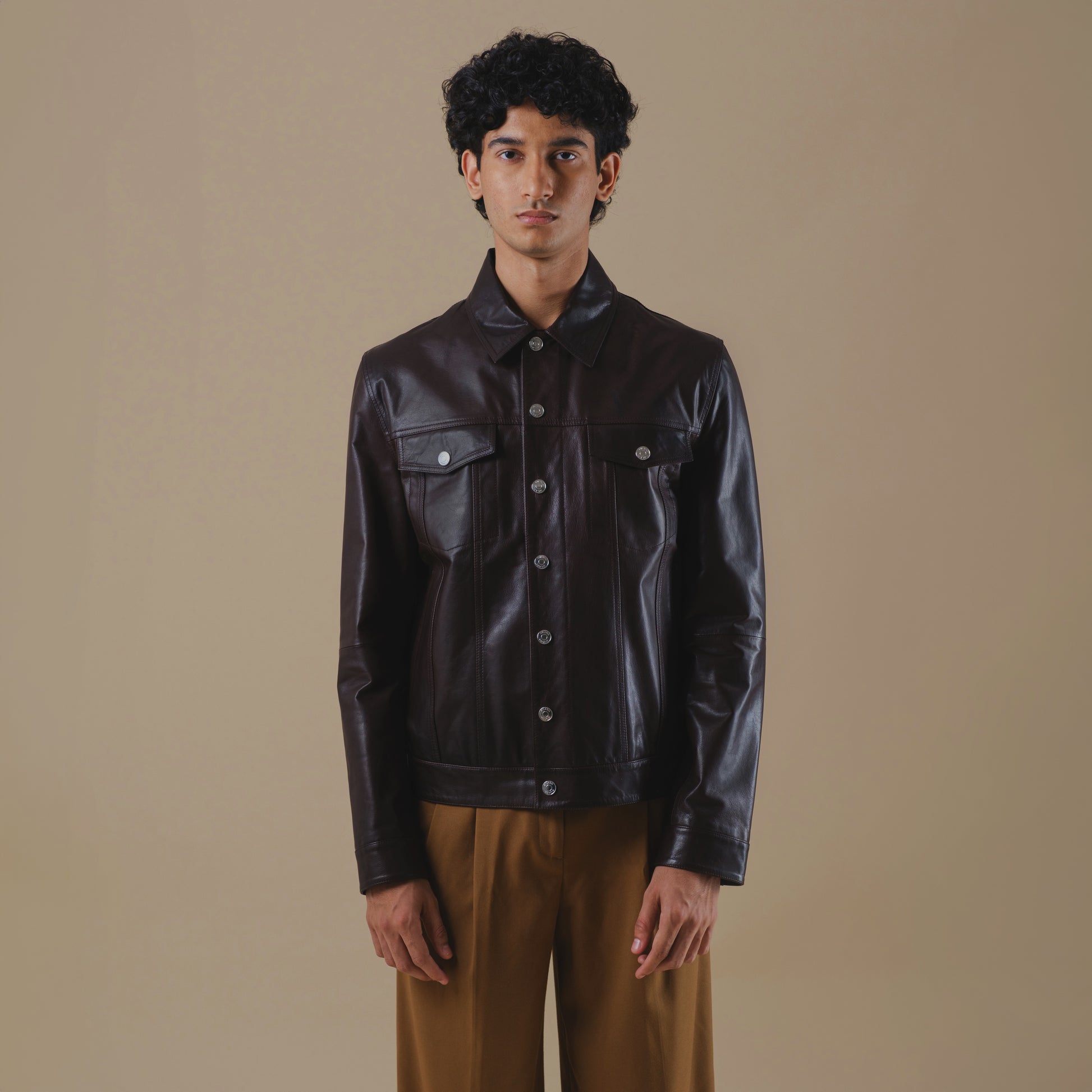 Man wearing a dark brown tucker leather jacket against a beige background