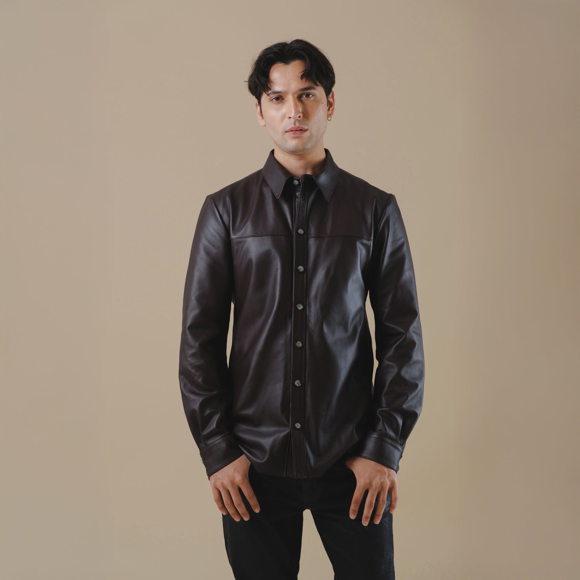 Man wearing a dark brown leather shirt against a beige background