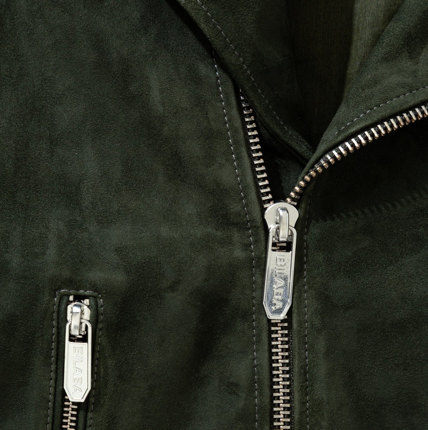 Close-up of a forest green colored jacket with zippers on a dark background