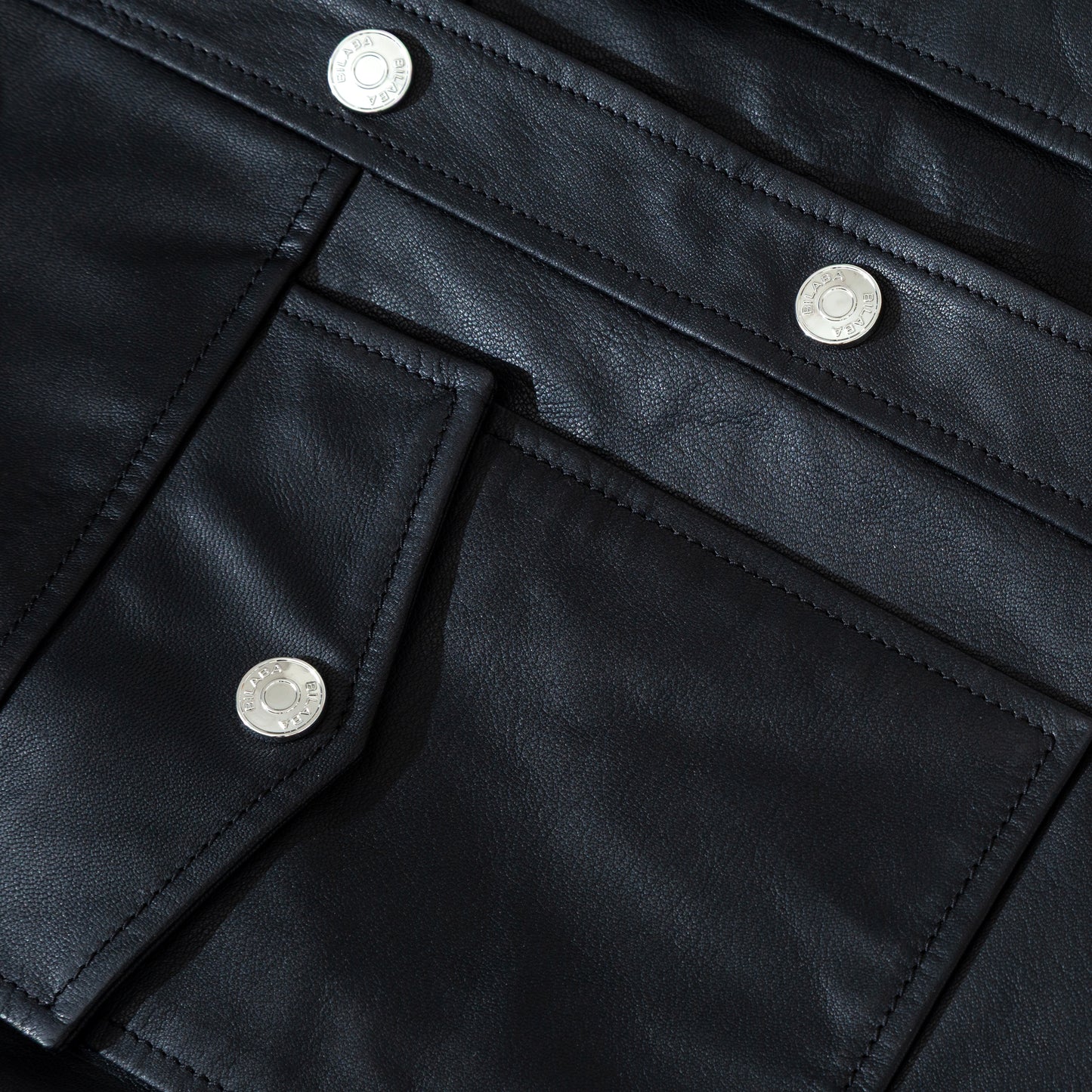 Close-up of a black trucker leather jacket with silver buttons