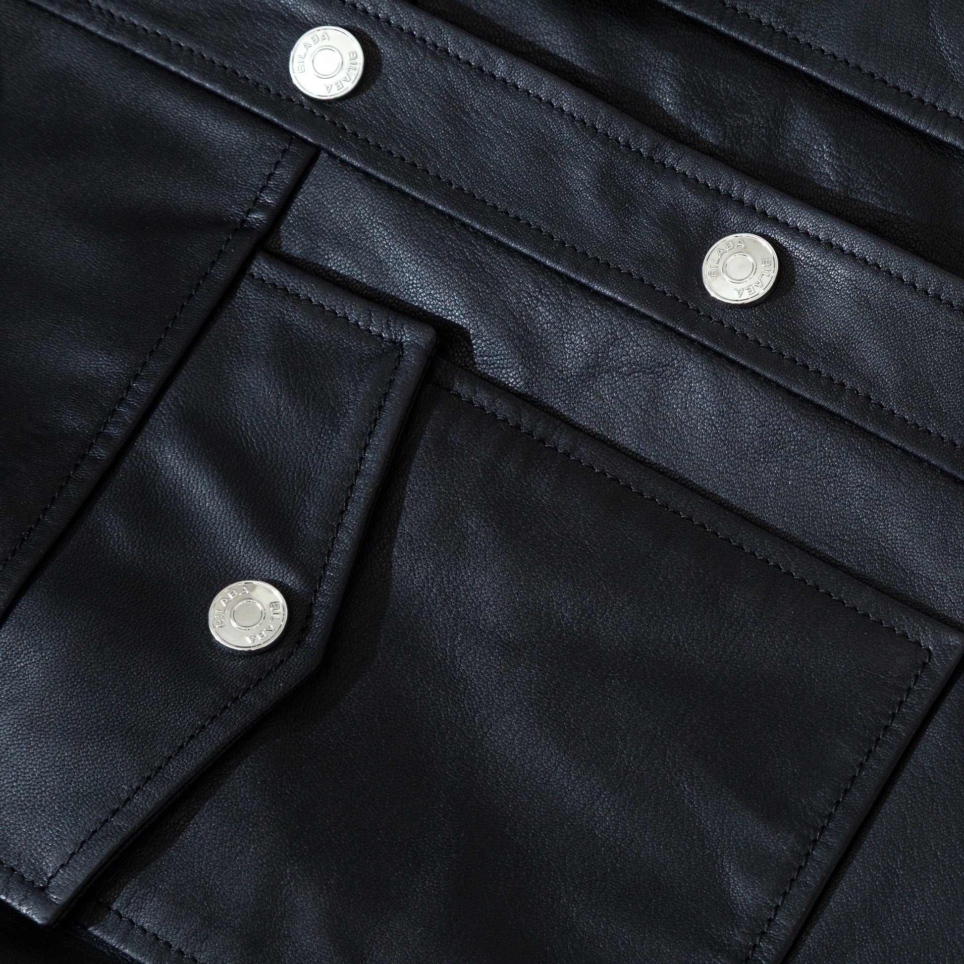 Close-up of a black trucker leather jacket with silver buttons