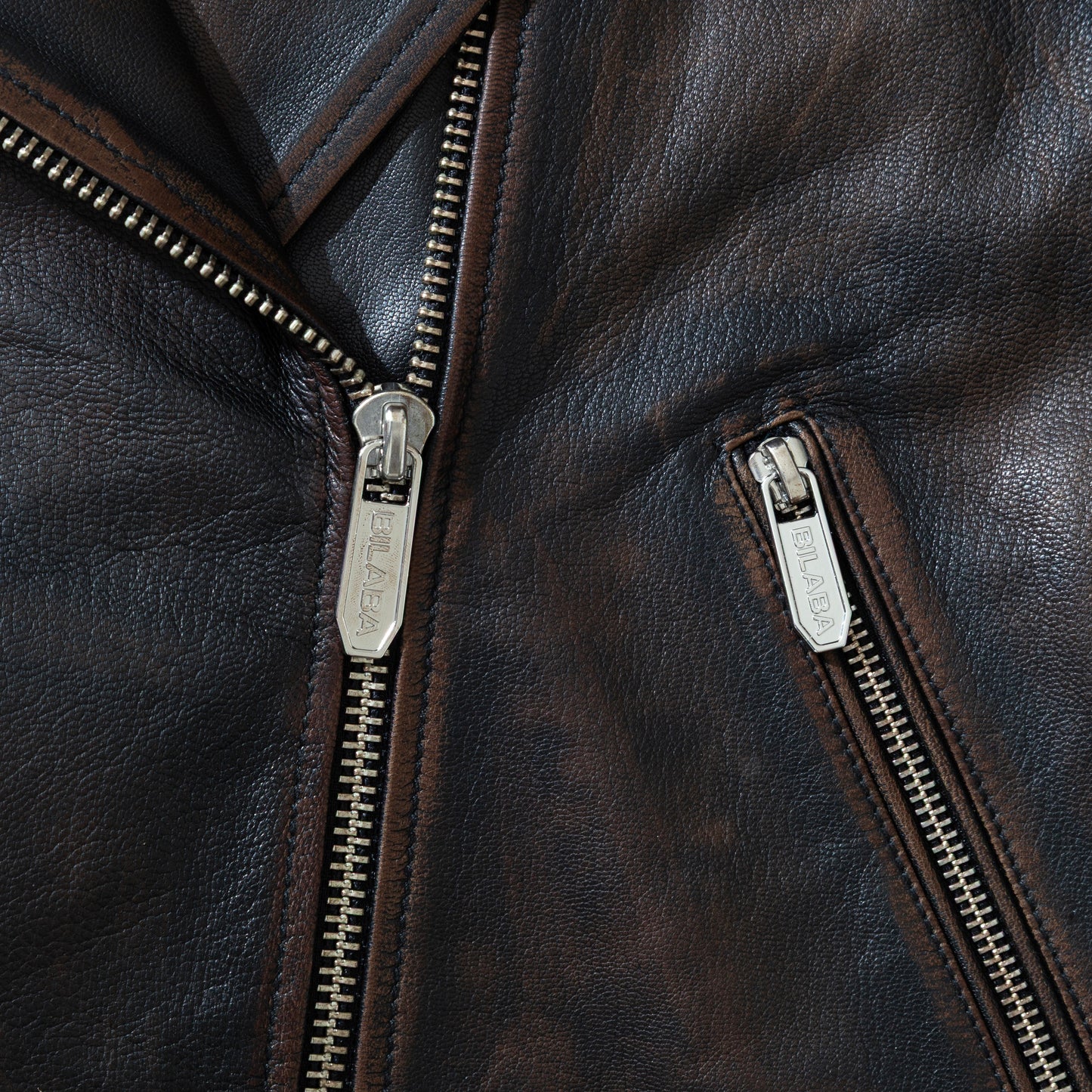 Close-up of a vintage black leather biker jacket with zippers