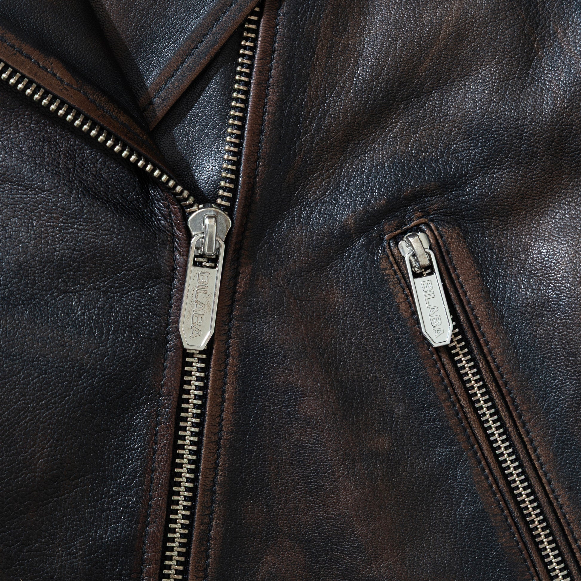 Close-up of a vintage black leather biker jacket with zippers
